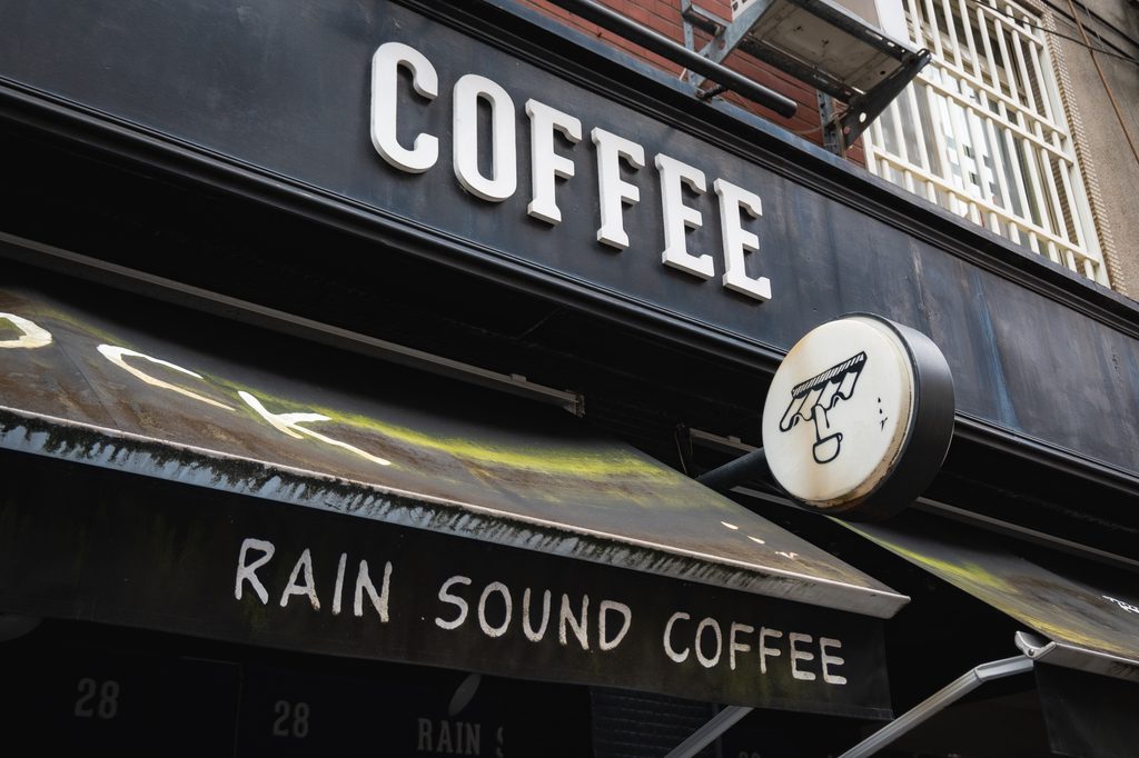 雨聲咖啡招牌特寫,黑底白字 COFFEE 與 RAIN SOUND COFFEE,旁邊掛著咖啡杯造型的圓形立體招牌
