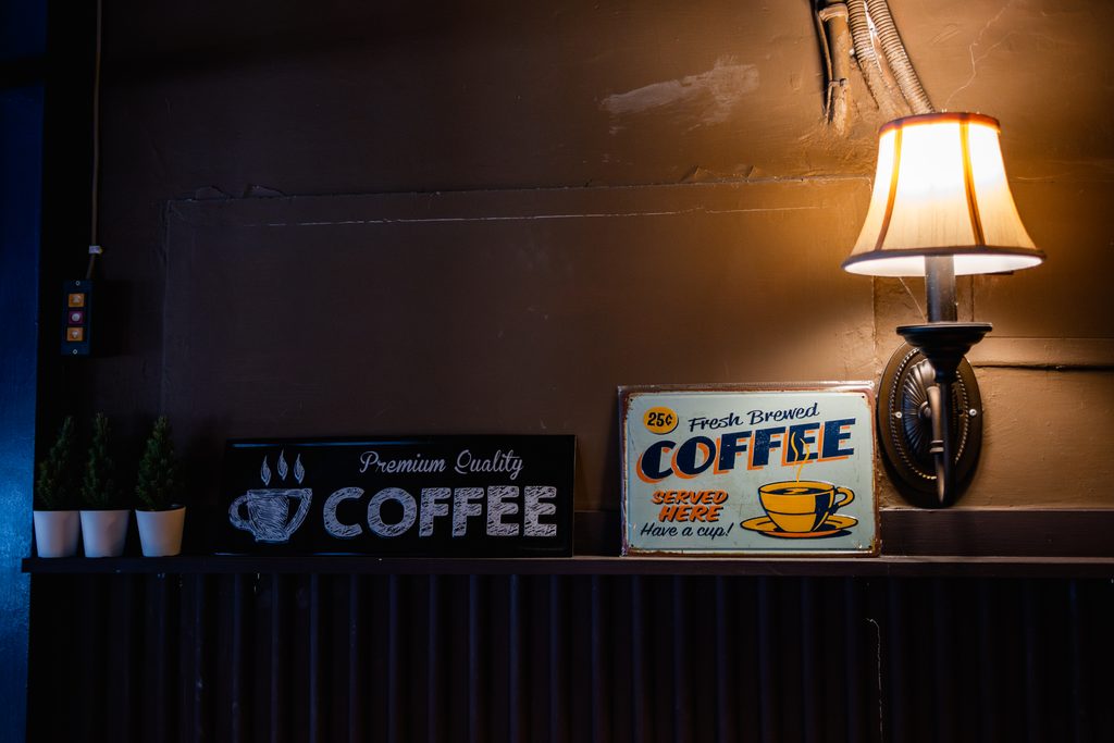 雨聲咖啡牆上的復古 COFFEE 鐵牌與英倫風壁燈裝飾