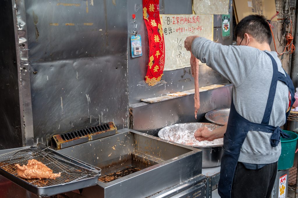 阿角紅燒肉店員從白色粉盆裡拿起剛裹好粉的豬肉，準備下油鍋現炸