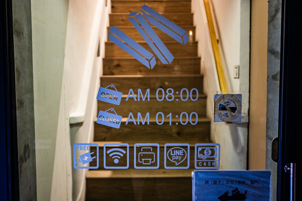 一樓玻璃門上的營業時間貼紙 AM 08:00 到 AM 01:00，下方五個圖示：插座、WiFi、列印、LINE Pay、現金