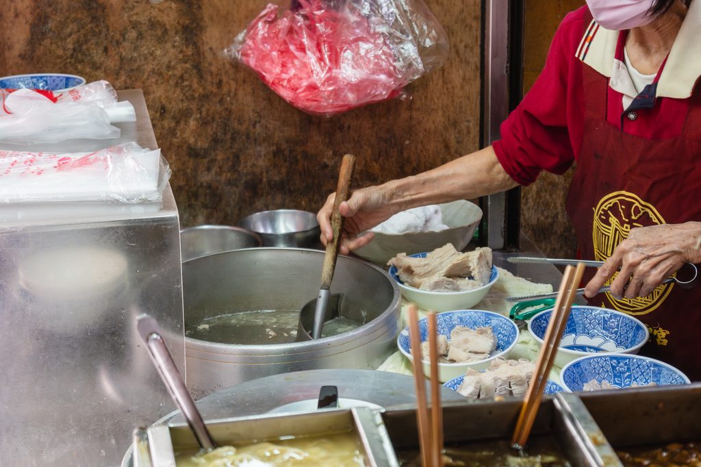 阿桂姨攤位上的大鍋，店員正從湯裡撈起排骨，蒸氣瀰漫