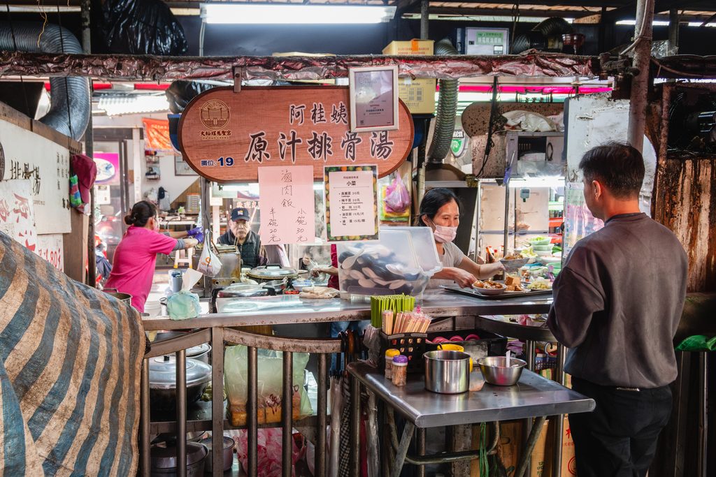 慈聖宮美食街的阿桂姨原汁排骨湯攤位正面，木質招牌與排隊的客人
