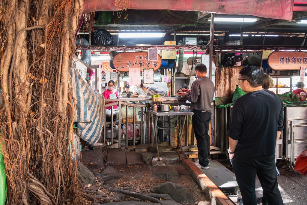 保安街49巷內的慈聖宮美食街街景，兩排小吃攤與垂下的老榕樹氣根