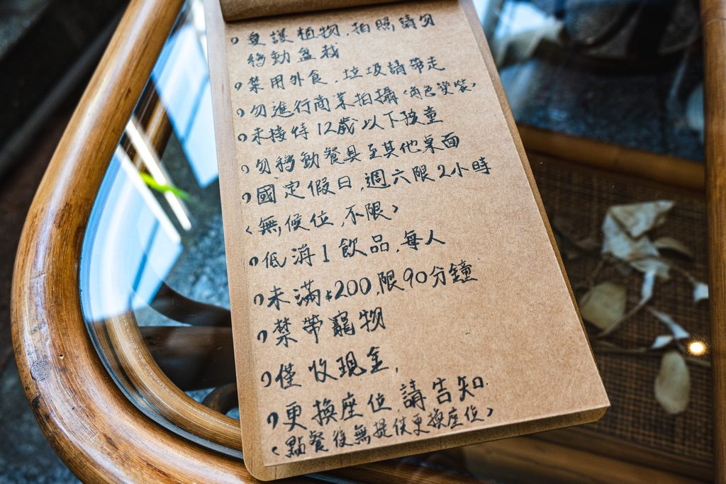 何家人珈琲的手寫店規,列出愛護植物、禁用外食、未接待12歲以下孩童、低消一杯飲品、未滿200元限90分鐘、禁帶寵物、僅收現金、點餐後不提供更換座位等規定