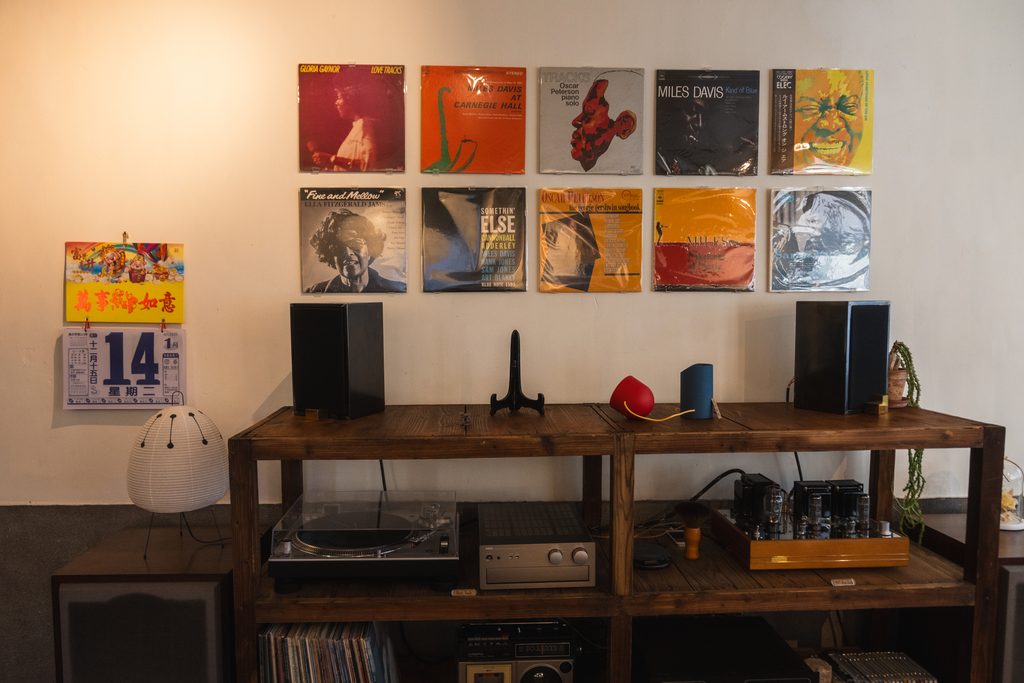 店內的黑膠唱片牆與唱盤,下方是真空管擴大機與喇叭,牆上掛著 Miles Davis 等爵士唱片封面