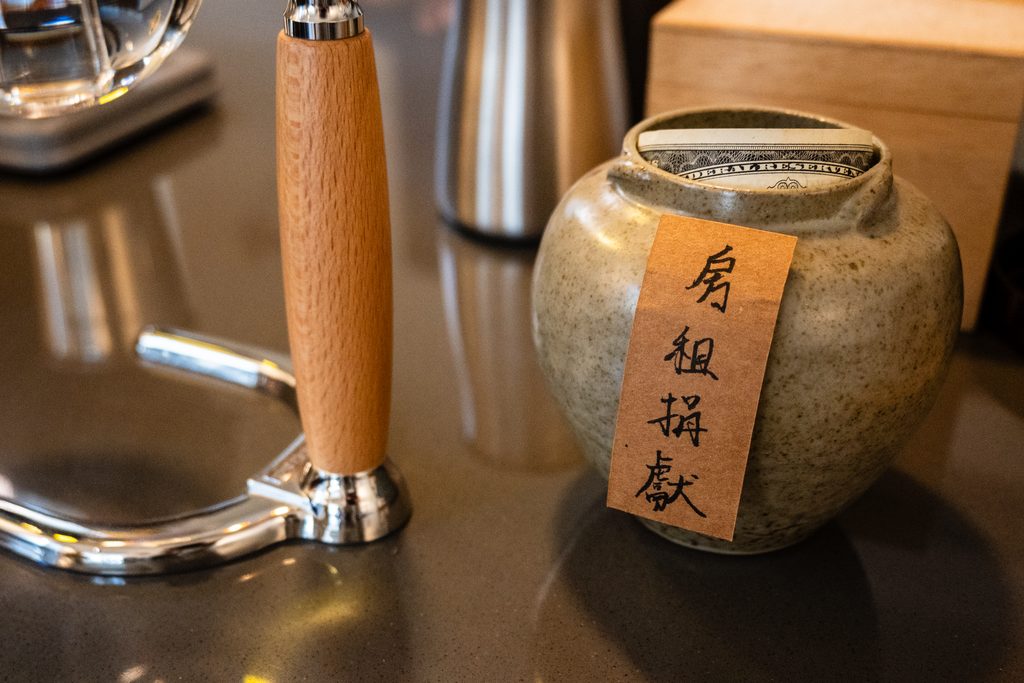 吧檯上的手沖壺旁邊放著一個陶罐,上面貼著「房租捐獻」四個字