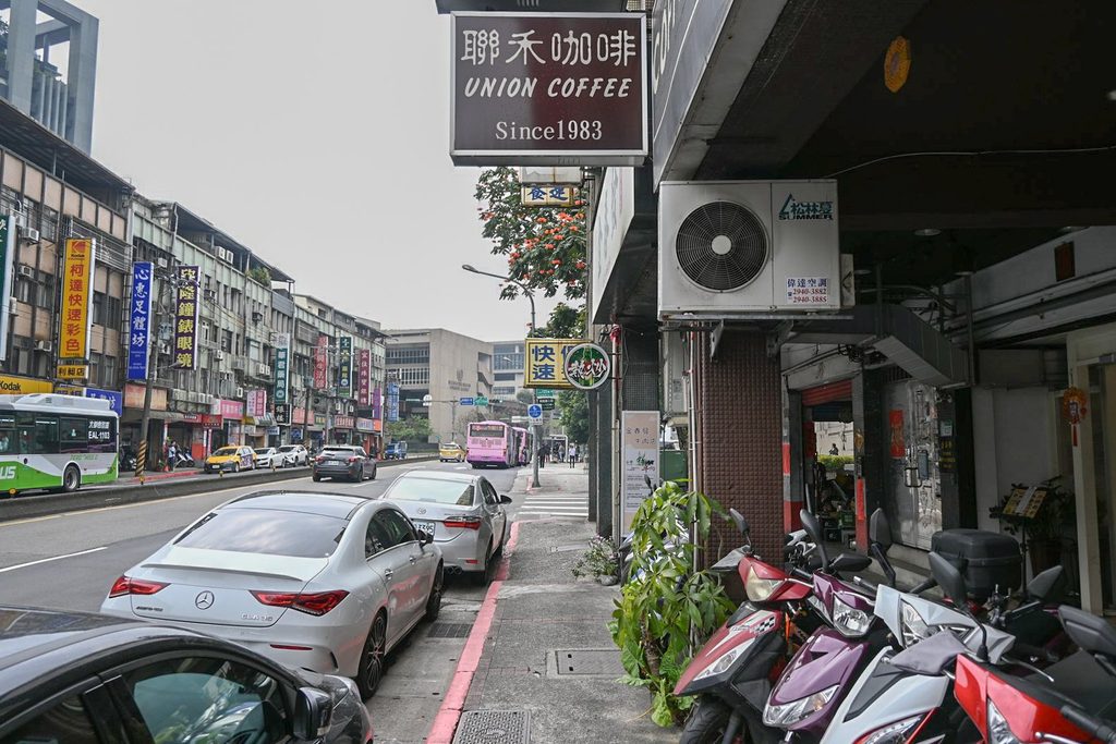 興隆路二段的白天街景,人行道旁一排店面,聯禾咖啡的招牌掛在騎樓上方