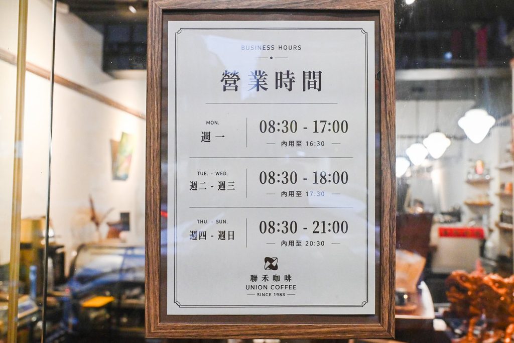 木框裱起來的營業時間牌,分成週一、週二至週三、週四至週日三段,每段下面標著內用到幾點,底部印著聯禾咖啡 UNION COFFEE SINCE 1983